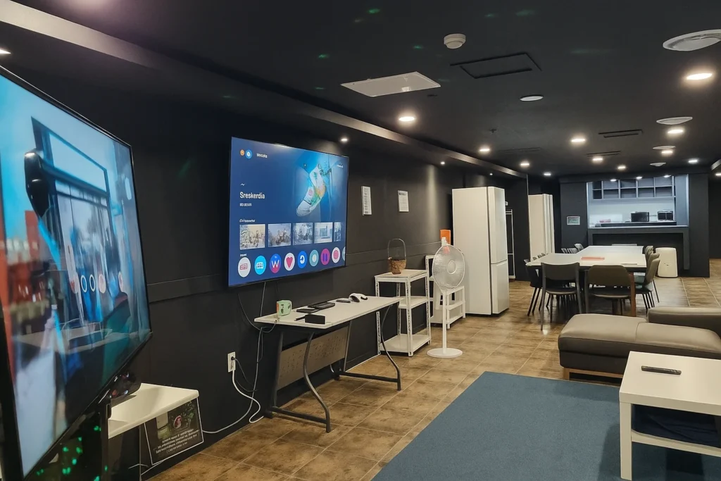 PS5 lounge with large screen and kitchen behind